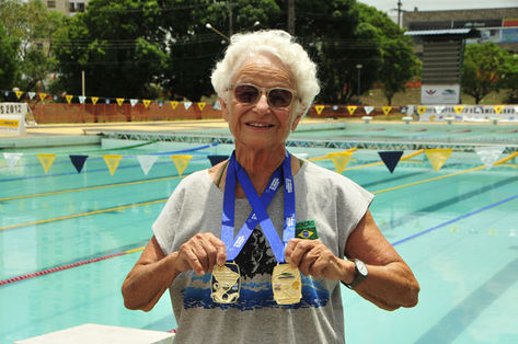 A campeã exibindo as muitas medalhas que já conquistou na natação